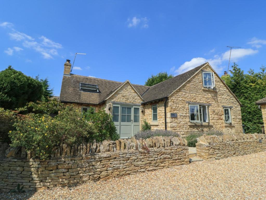 a stone house with a stone wall at 12 Manor Farm Close in Kingham