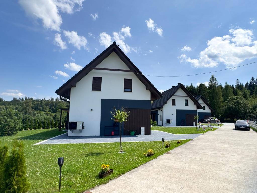 a white house with a black roof at Agroturystyka Nad Lasem - Domki w górach in Toporzysko