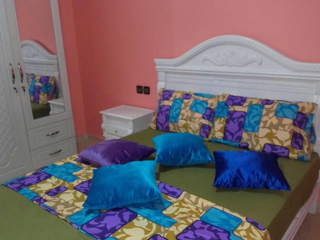een slaapkamer met een bed met blauwe en paarse kussens bij Bienvenue chez vous in Kenitra