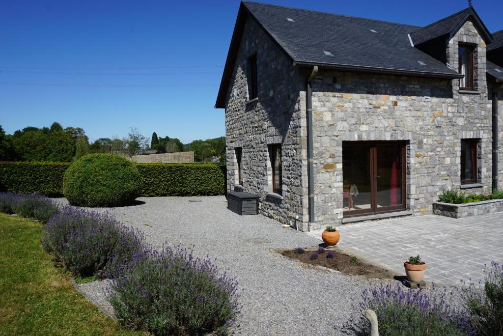 a stone house with a yard with purple flowers at Gîte du Vieux Chemin in Durbuy