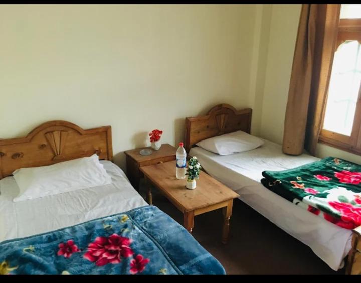 a bedroom with two beds and a table with flowers at Ibrahim lodge restaurant in Astor