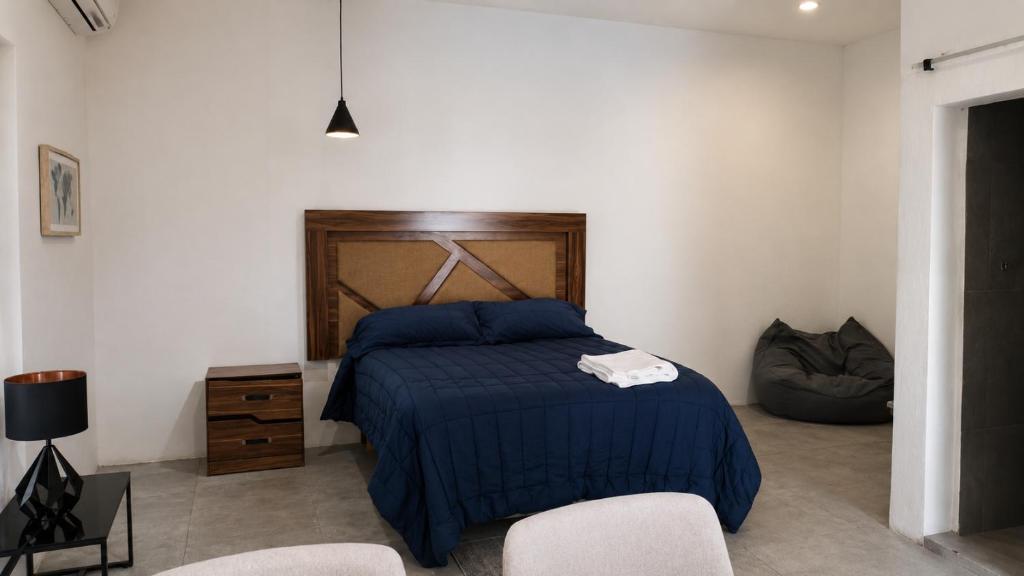 a bedroom with a bed with a blue comforter and two chairs at Suite privada con alberca - Cama Queen in El Centenario