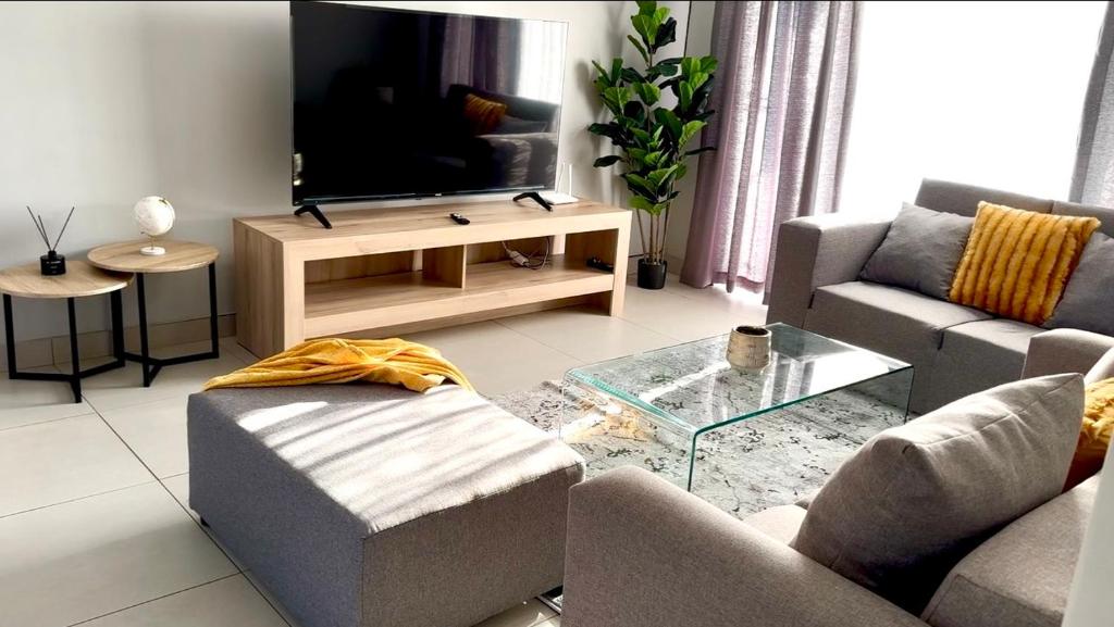a living room with a couch and a tv at Nova Apartments- MbabaneCBD in Mbabane