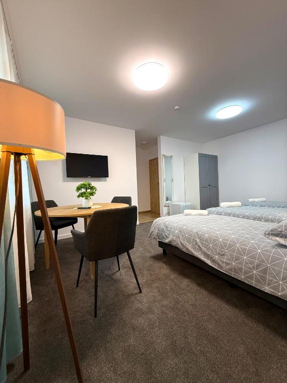 a bedroom with a bed and a table and a desk at DOBA RENT Wysockiego 104 in Białystok
