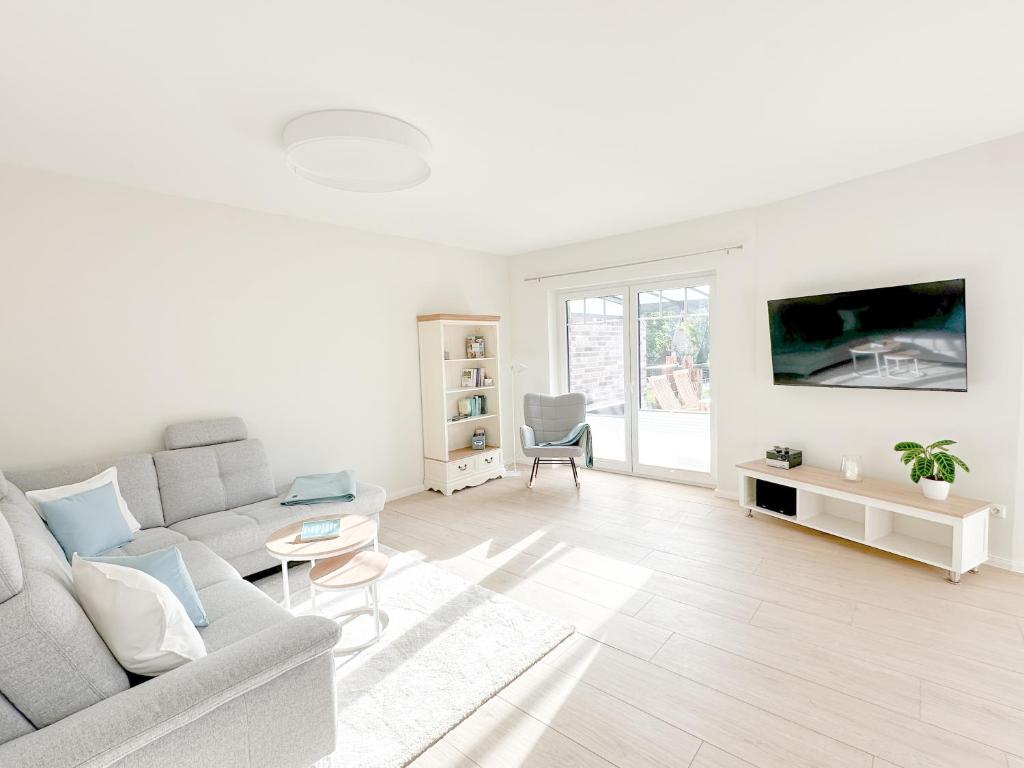 a white living room with a couch and a tv at Ferienwohnung Knut in Bornholt