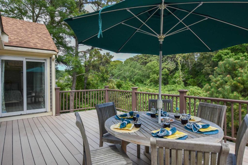 a wooden table with a green umbrella on a deck at 1 6 mi to Nauset Beach in Orleans