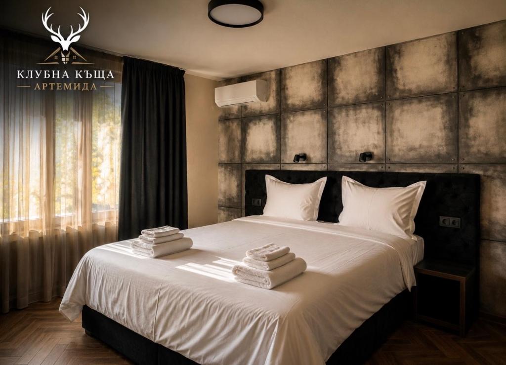 a bedroom with a large bed with towels on it at Клубна къща Артемида - Стая in Pravets