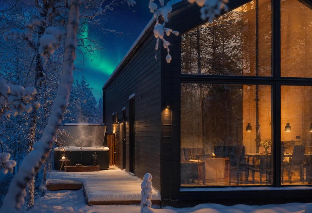 a house with a view of the northern lights in the snow at Ainur Villas in Saariselka