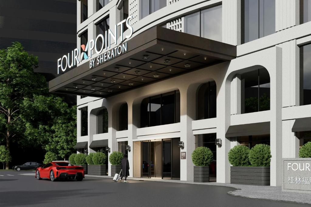a man standing in front of a building with a red car at Four Points by Sheraton Guilin Central in Guilin