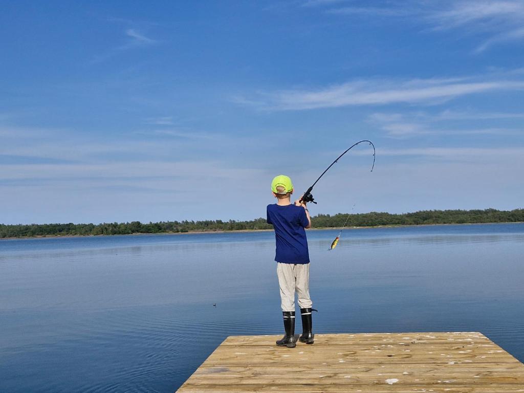 Ein Mann steht auf einem Steg und hält eine Angelrute. in der Unterkunft Utkiken in Eckerö
