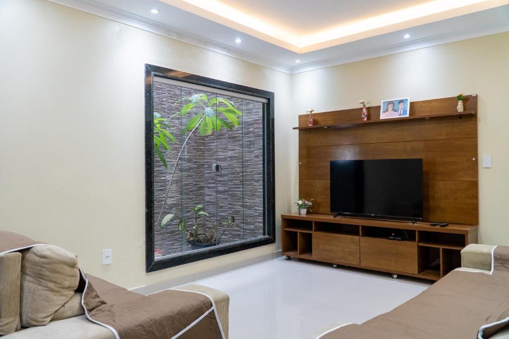 a living room with a large window and a flat screen tv at Estrela de Euclides in Euclides da Cunha