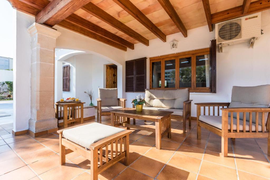 a patio with a table and chairs and wooden ceilings at Chalet Falcó with Private Pool and Garden in Port d'Alcudia