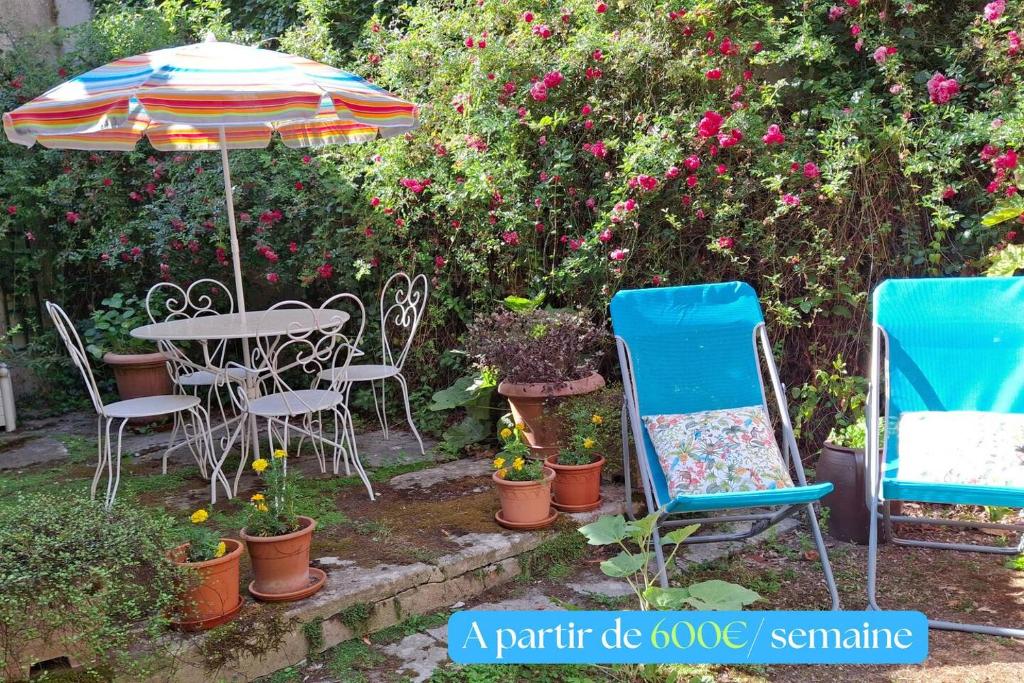 a table and chairs and an umbrella in a garden at Jardin et Hotel Particulier in Bayeux