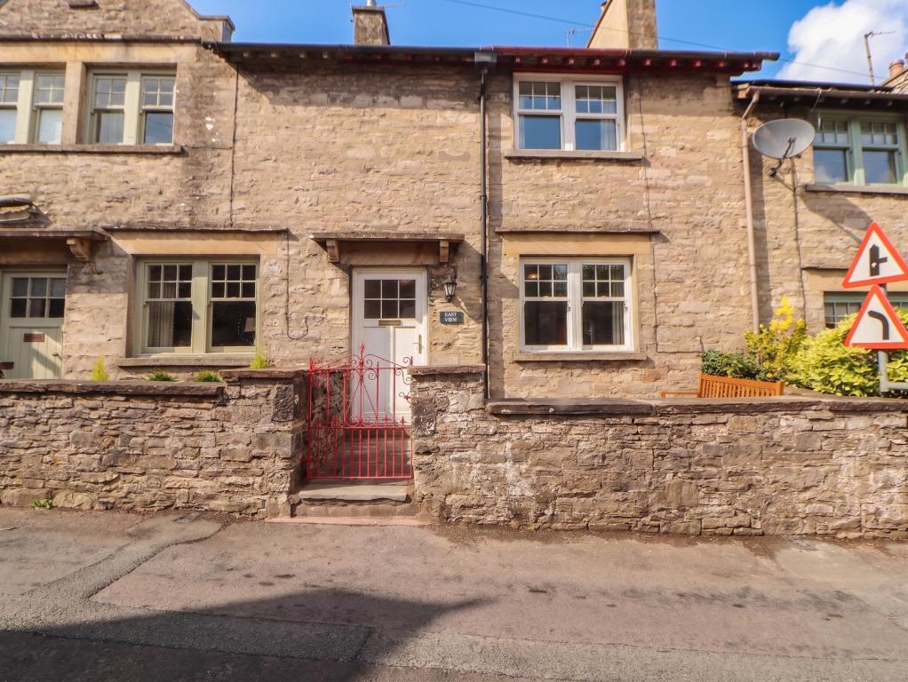 an old stone house with a red door and a yield sign at East View in Kirkby Stephen