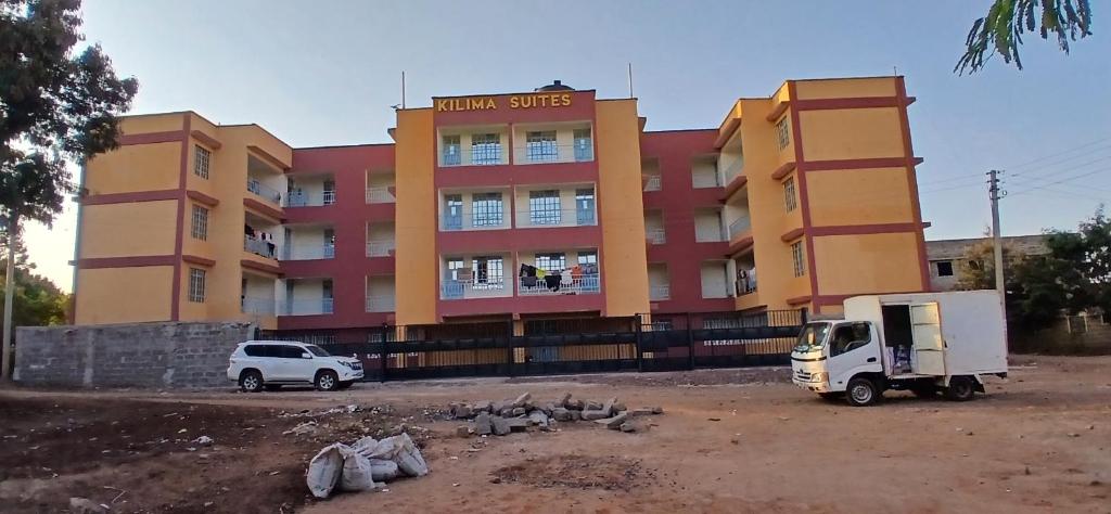 a building with a truck and pigeons in front of it at Kilima Suites in Taveta