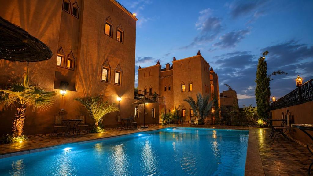 a swimming pool in front of a building at night at Riad Ouinz in Aït Benhaddou