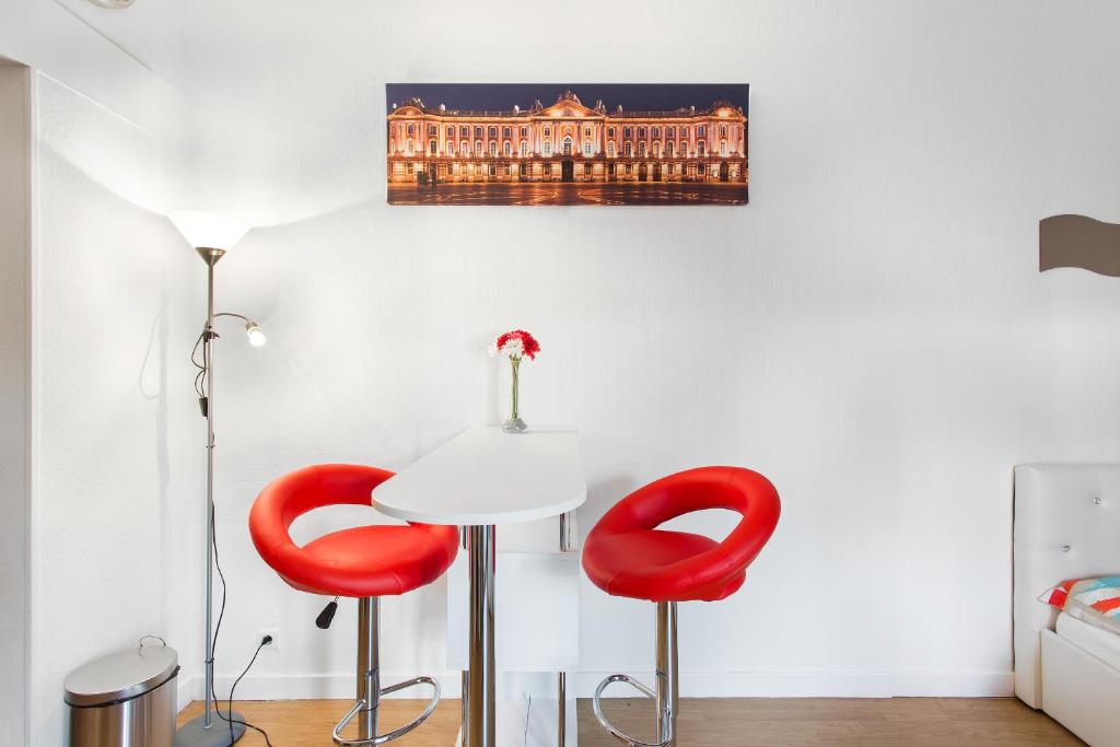 トゥールーズにあるNouvel Oasis Toulouse Saint Cyprienの赤い椅子2脚と壁画が備わるお部屋