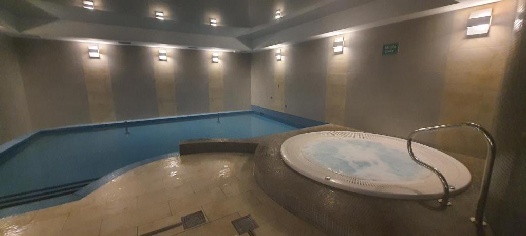 a bath tub in a room with a swimming pool at Triventi Apartament Rajski in Karpacz