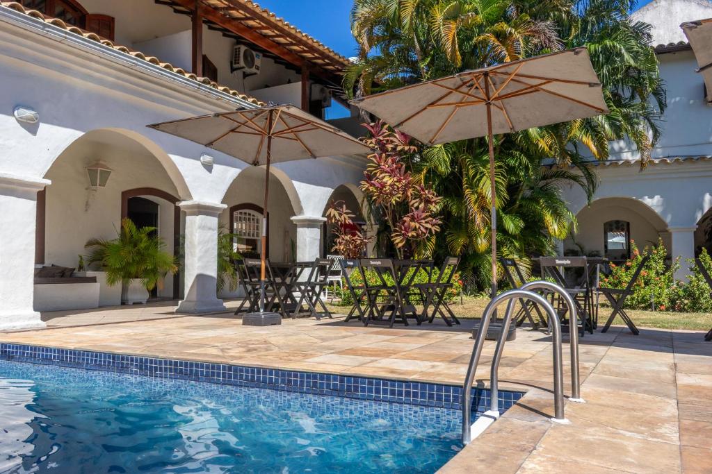 a swimming pool with two umbrellas and a house at Pousada Boulevard in Cabo Frio