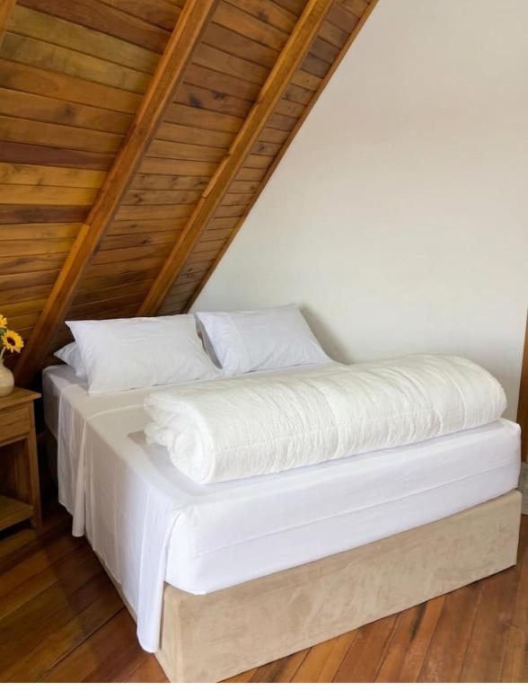 a bed with white sheets on it in a room at Pousada Canto Gira Sol Estúdio Beija Flor 2º Andar 5 Min do Beto Carrero Penha SC in Penha