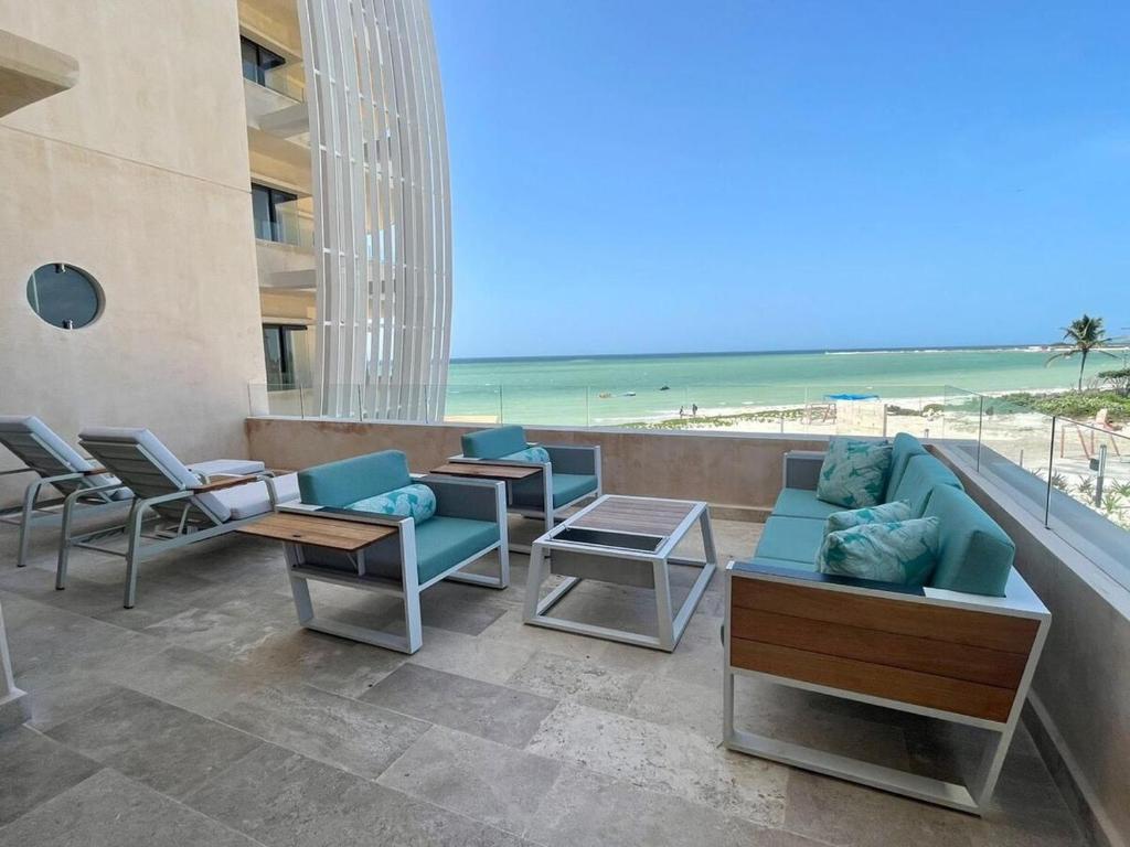a patio with chairs and tables and the beach at Beachfront condo in Progreso in Telchac Puerto