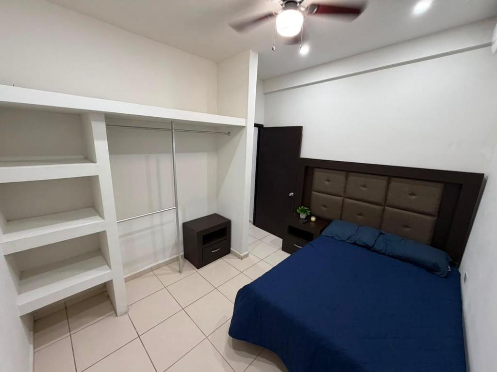 a bedroom with a bed with a blue blanket and shelves at Departamentos MIRAMONTES in Guaymas