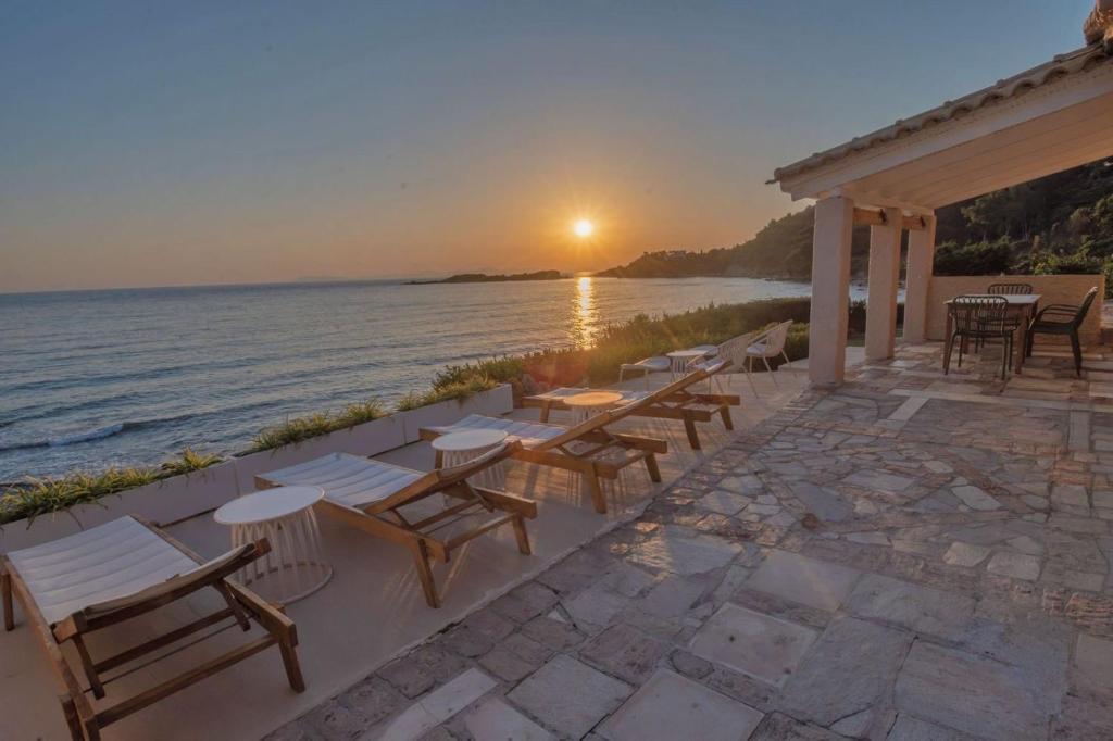 a patio with tables and chairs next to the water at Casa del mare in Pyrgos