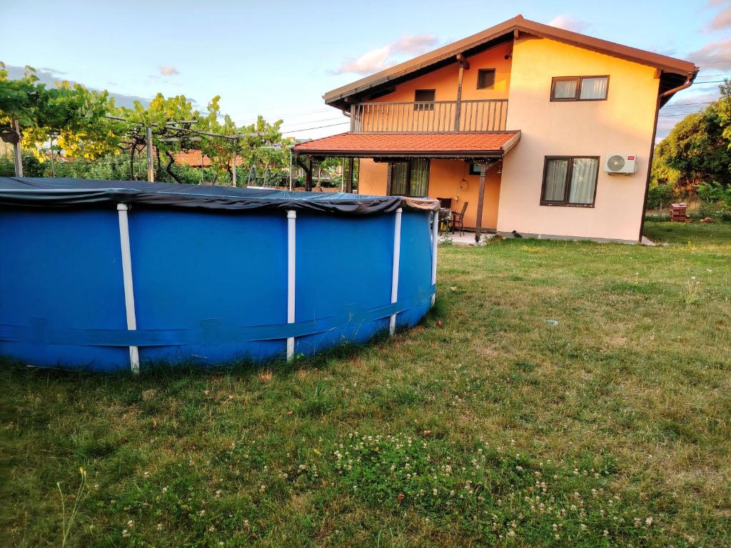 a house with a blue container in a yard at Къща за гости Азария in Resilovo