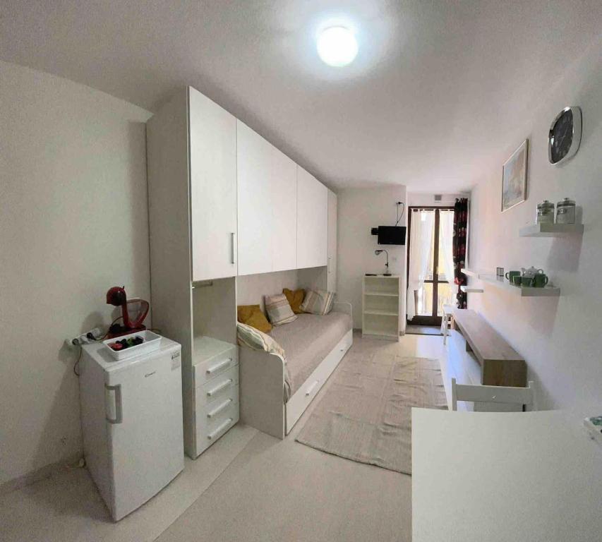 a white living room with a couch and a table at Studio apartment on the lake in Lovere