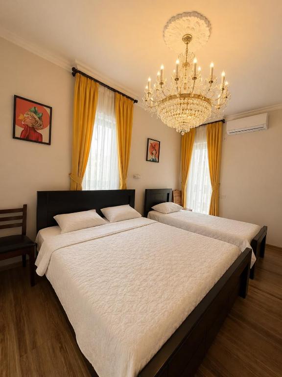 two beds in a bedroom with a chandelier at Four seasons in Kutaisi