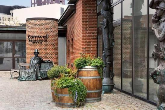 a statue of a man sitting on a bench in front of a building at Comwell in Odense