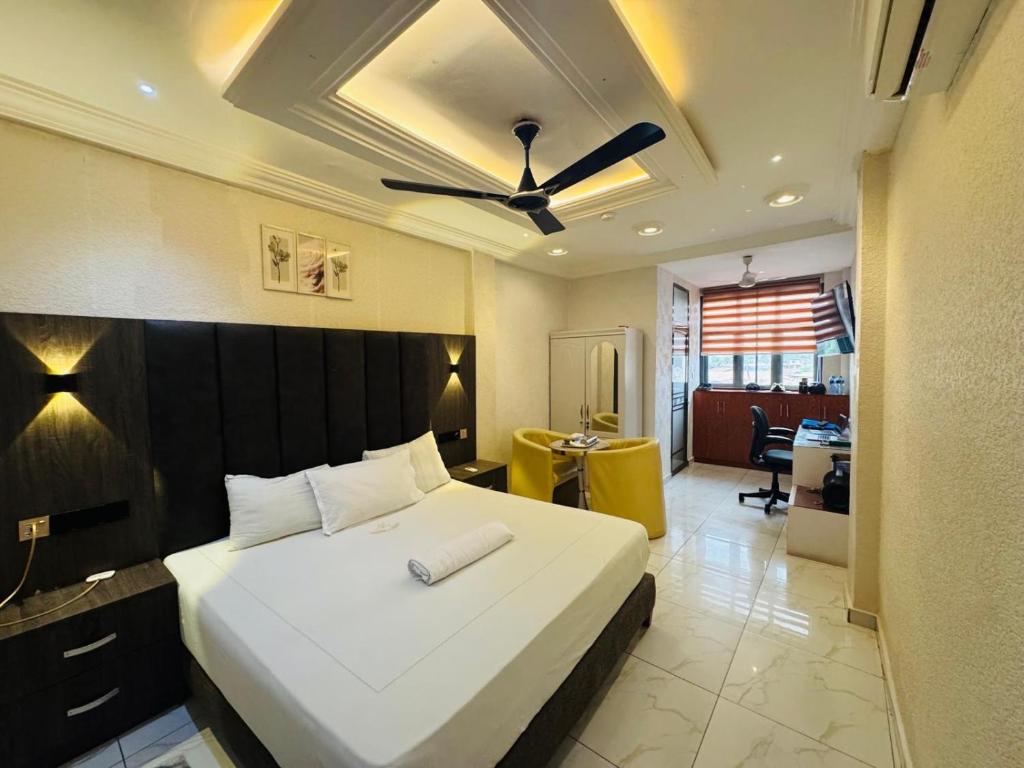 a bedroom with a large bed with a ceiling fan at Texas Royal Hotel in Pokuase