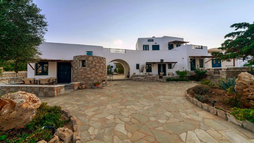 a large white house with a stone patio at Coral Apartments in Karavostasi