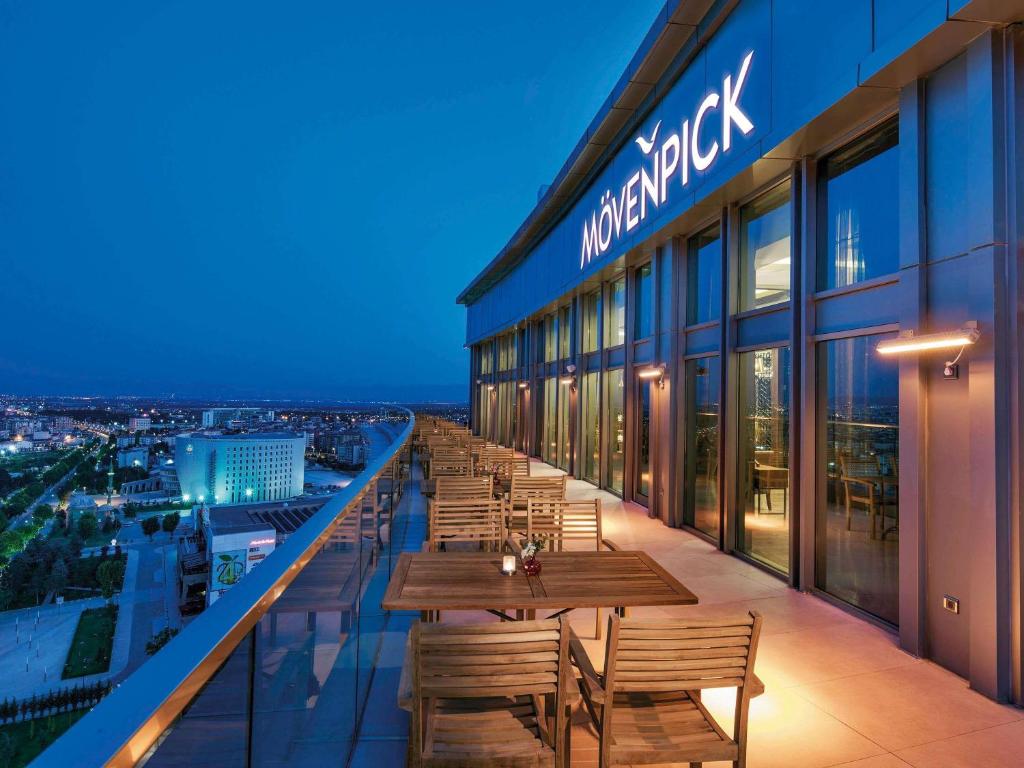a restaurant with wooden tables and chairs on a balcony at Movenpick Hotel Malatya in Malatya