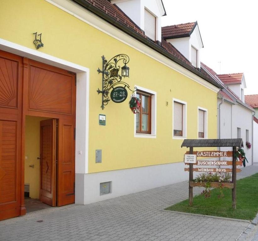 ein gelbes Gebäude mit einer Uhr auf der Seite in der Unterkunft Gästezimmer Poys in Auersthal