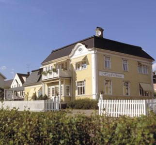 a large yellow house with a white fence in front of it at Hotell Örnen in Torsby