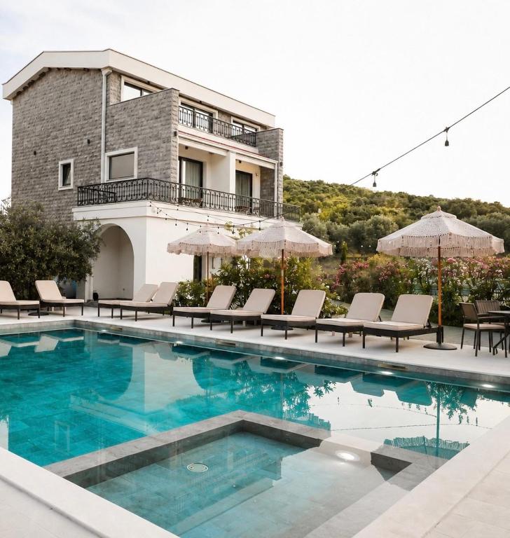 a swimming pool with chairs and a house at Carolea Villas - Boutique Hotel & Villas in Ulcinj