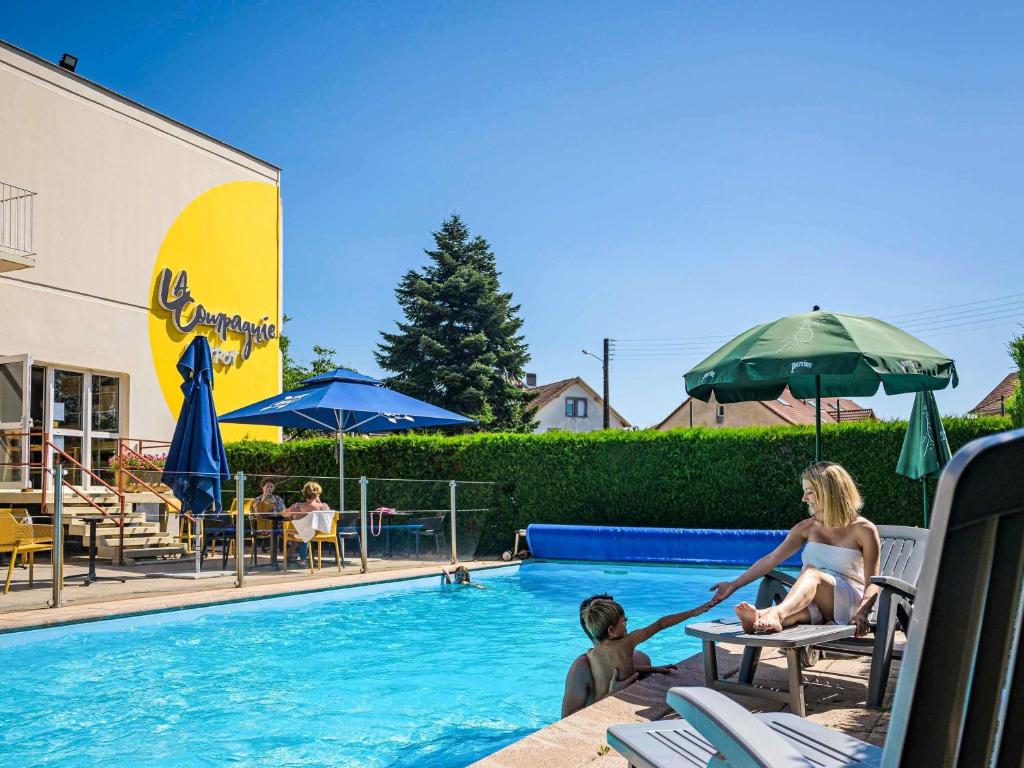 a woman and a child playing in a swimming pool at ibis Belfort Danjoutin in Belfort