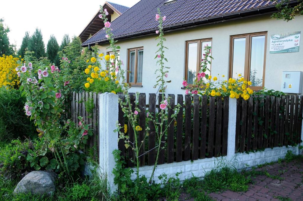 a fence in front of a house with flowers at Gospodarstwo Agroturystyczno-Edukacyjne Gratka in Celiny