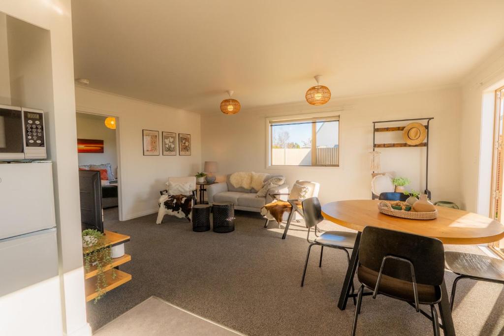 a living room with a table and a kitchen at Relax on Rata, Cottage 2 in Twizel