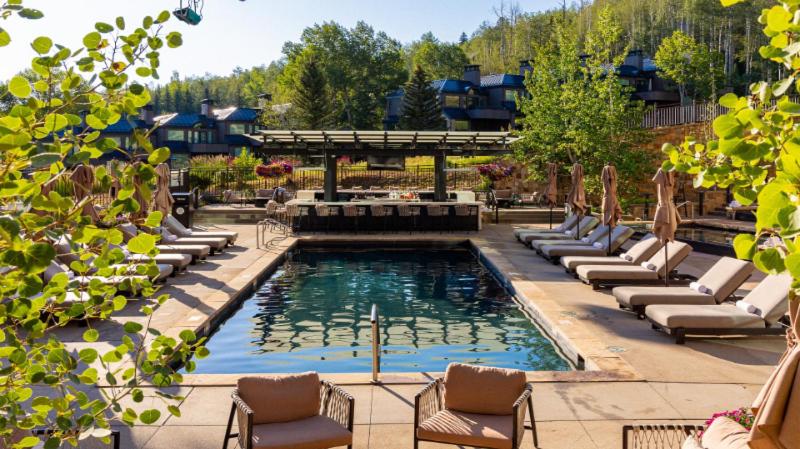 a swimming pool with lounge chairs and a fountain at Viceroy Snowmass in Snowmass Village