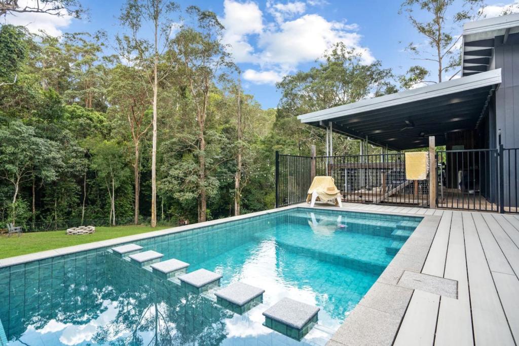 a swimming pool with a deck and a house at Creekside Cottage, pet friendly w pool in Perwillowen