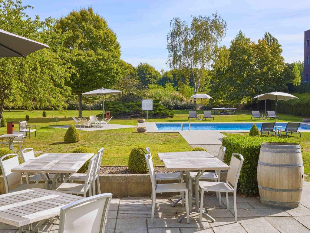 a patio with tables and chairs and a pool at Novotel Antwerpen - Ekeren in Antwerp
