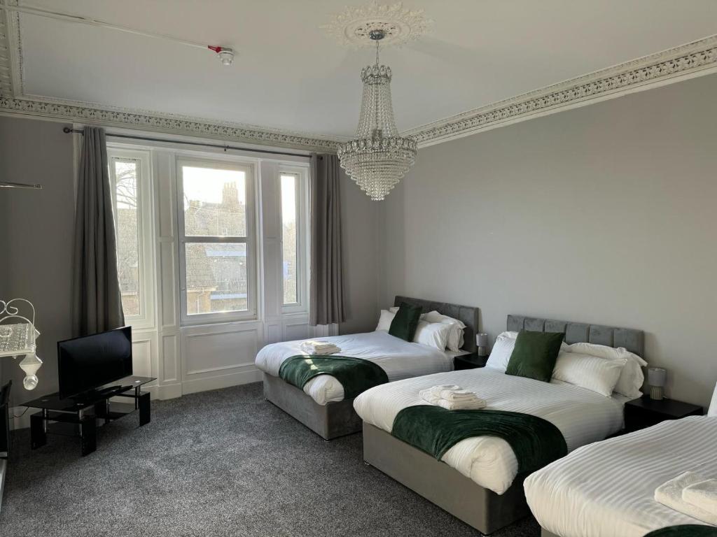 a bedroom with two beds and a chandelier at Edinburgh City Hotel in Edinburgh