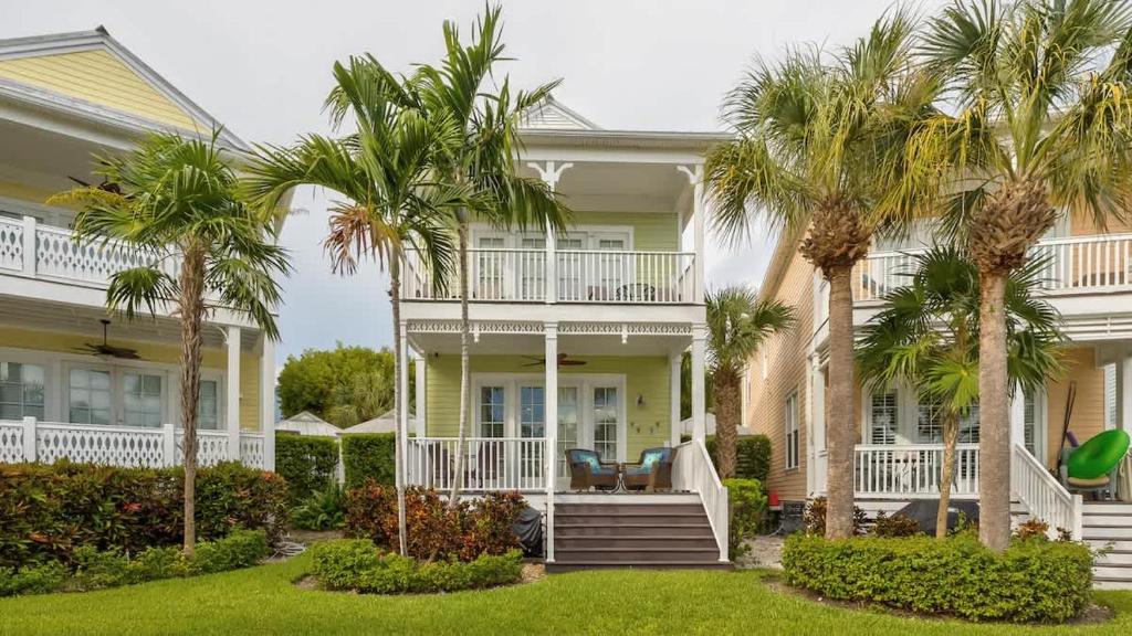a white house with palm trees in front of it at Pristine Islamorada Pool Home with Ocean View and Dockage in Islamorada