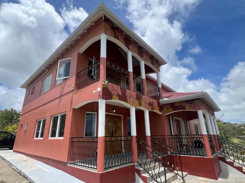 a red house with a balcony on a street at Private Executive Master Suite - Parham, Antigua in Vernons