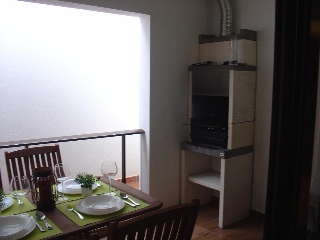 une table à manger avec des assiettes et un four micro-ondes dans l'établissement Apartamento Sol e Mar, à Monte Gordo