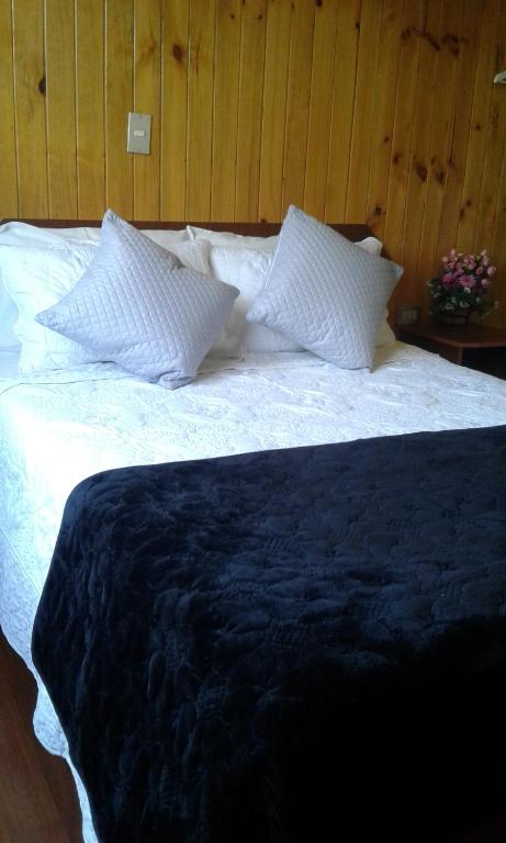 a large bed with white sheets and pillows at Residencial del Maule in Linares
