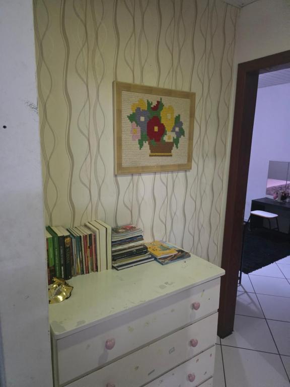 a bedroom with a dresser with books on it at Pousada de Isa in Palhoça