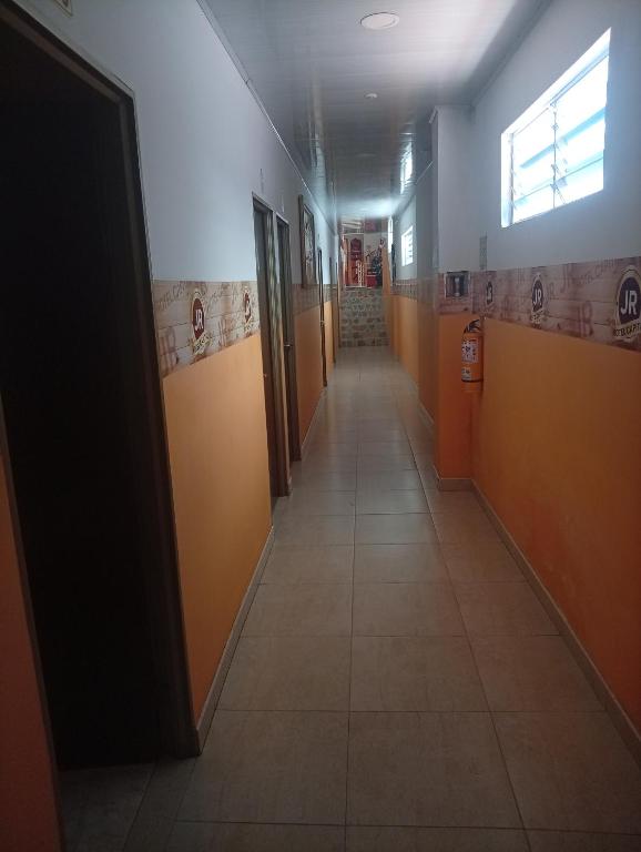 a hallway in a building with orange doors and tile floors at Hotel capital in Florencia
